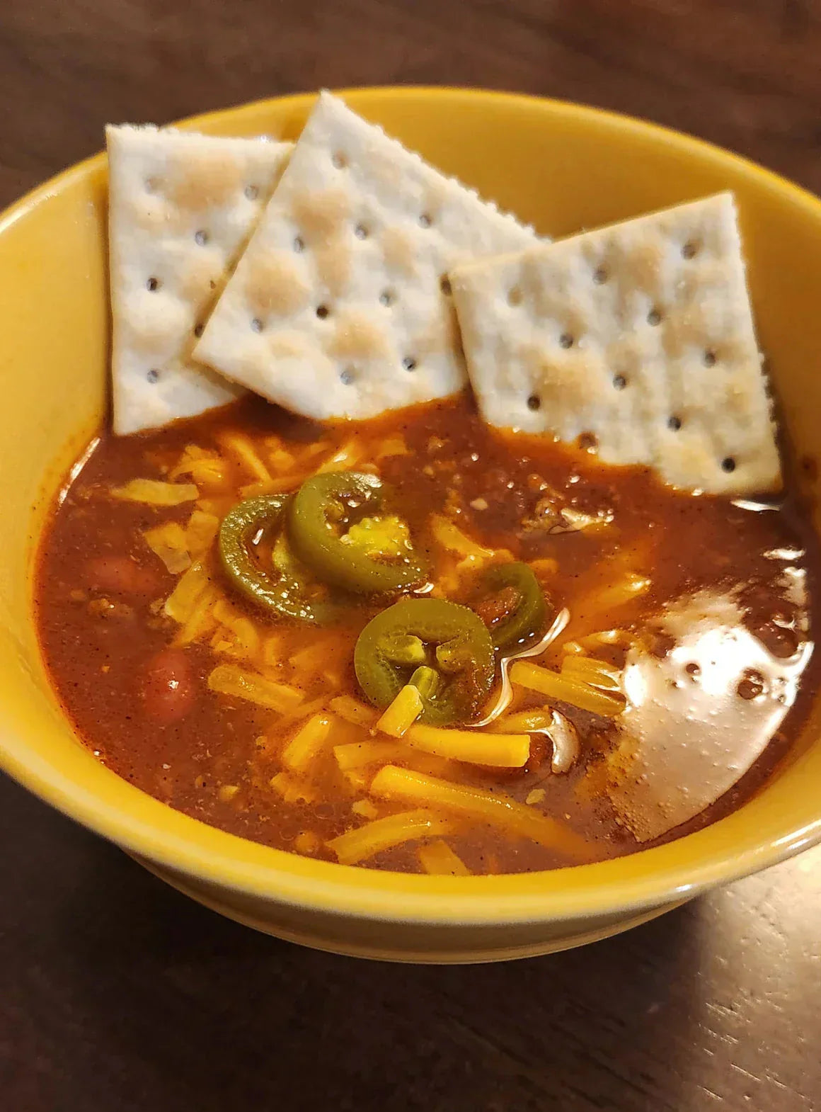 A hearty bowl of Diamond R beef chili topped with shredded cheddar, jalapenos, and sour cream