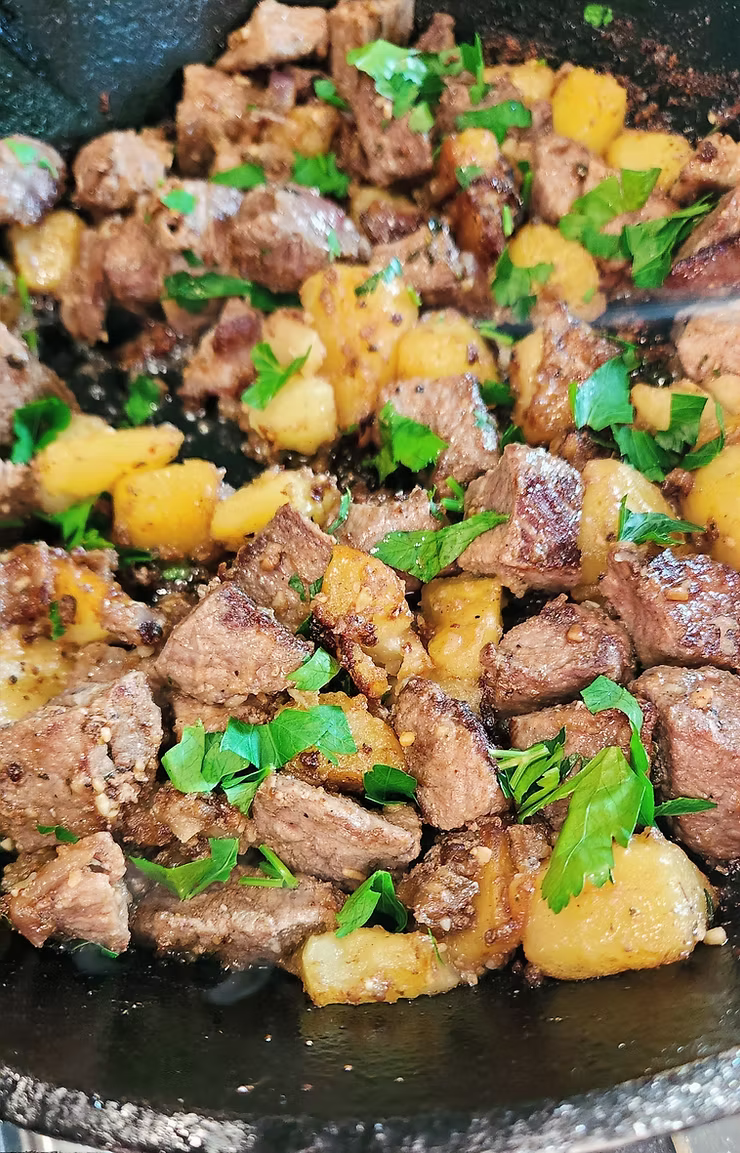 Buttery steak bites with potatoes and herbs in a cast iron skillet